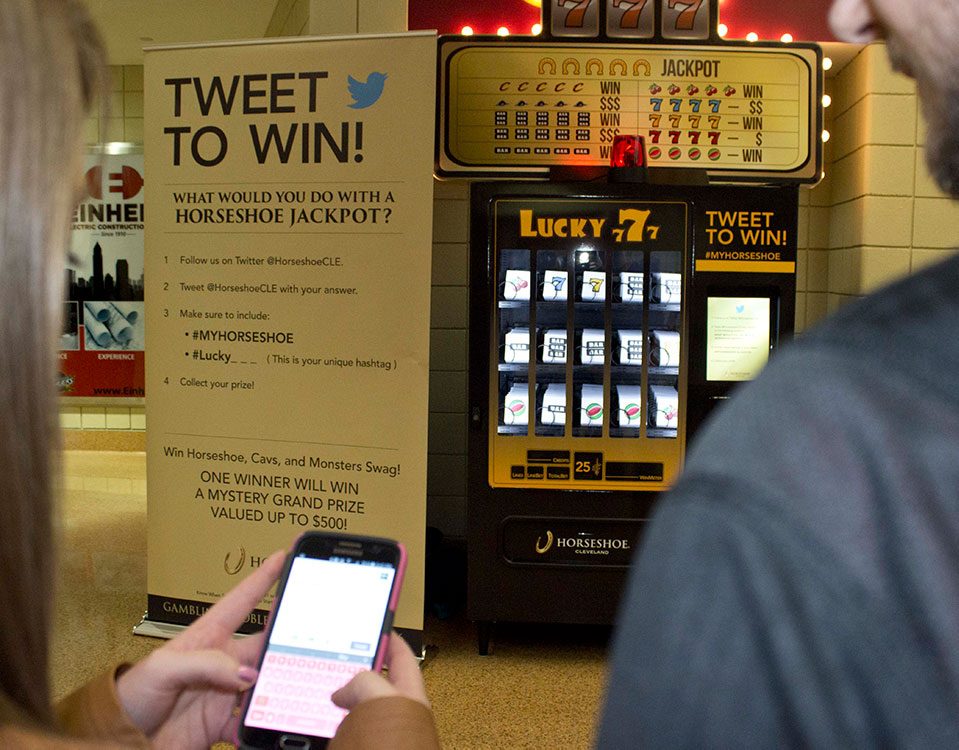 Person on their phone using twitter to tweet for a prize in front the interactive vending machine design